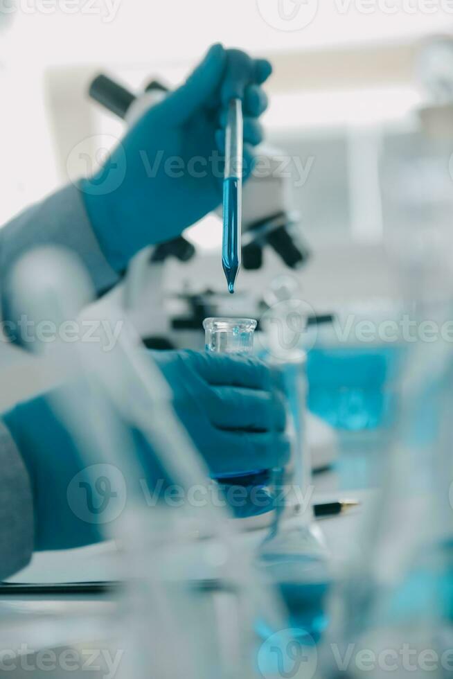 biochemical research scientist team working with microscope for coronavirus vaccine development in pharmaceutical research labolatory, selective focus photo