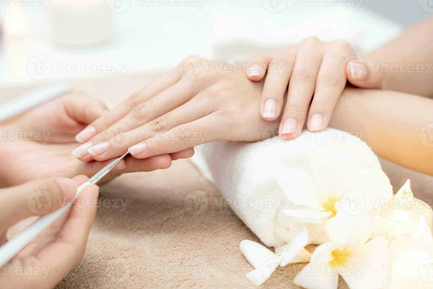 la mujer recibe el servicio de atención de la manicura esteticista profesional en el centro de spa. el salón de belleza de uñas usa una lima de uñas para el tratamiento de acristalamiento. manicurista hace que el cliente de uñas sea hermoso. tratamiento de spa para el cuidado del cuerpo foto