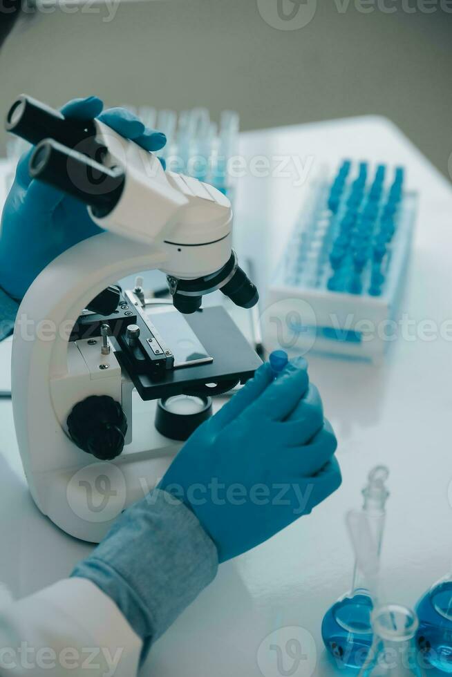 biochemical research scientist team working with microscope for coronavirus vaccine development in pharmaceutical research labolatory, selective focus photo
