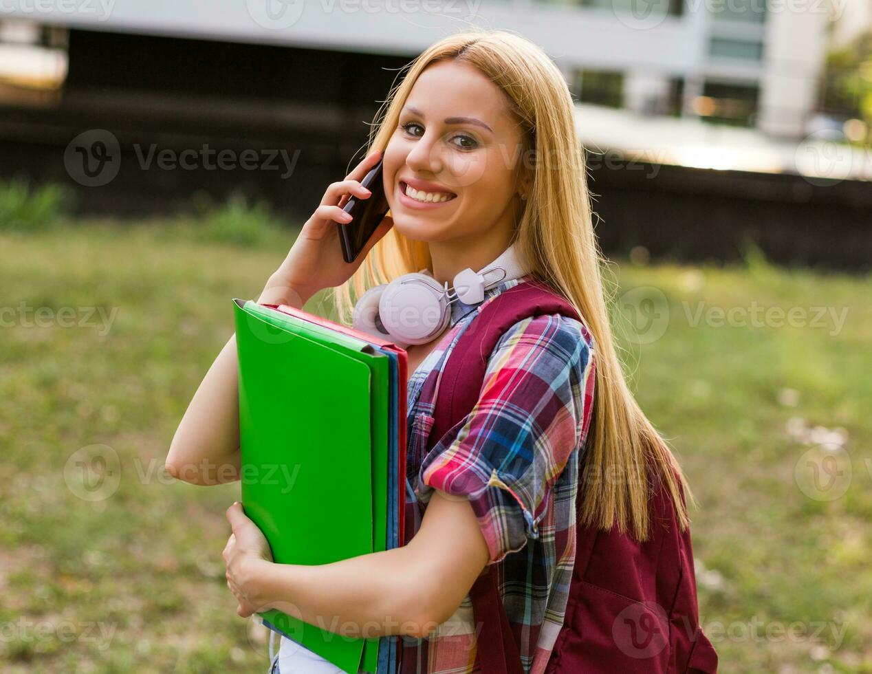 Female student with headphones using mobile phone outdoor. photo