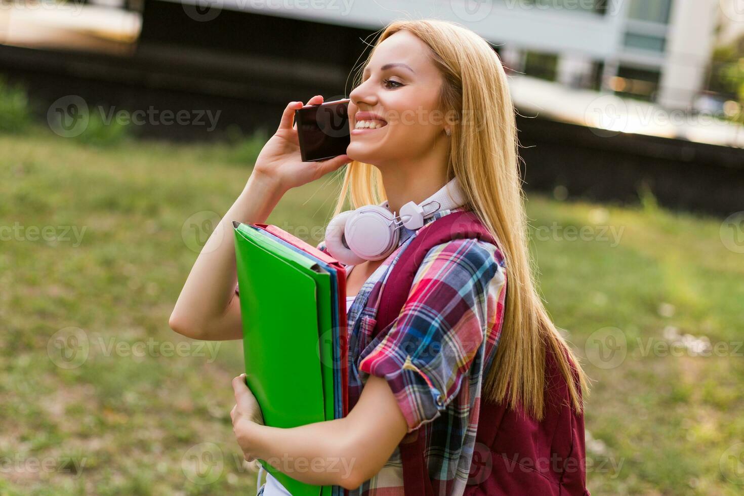 Female student with headphones using mobile phone outdoor. photo
