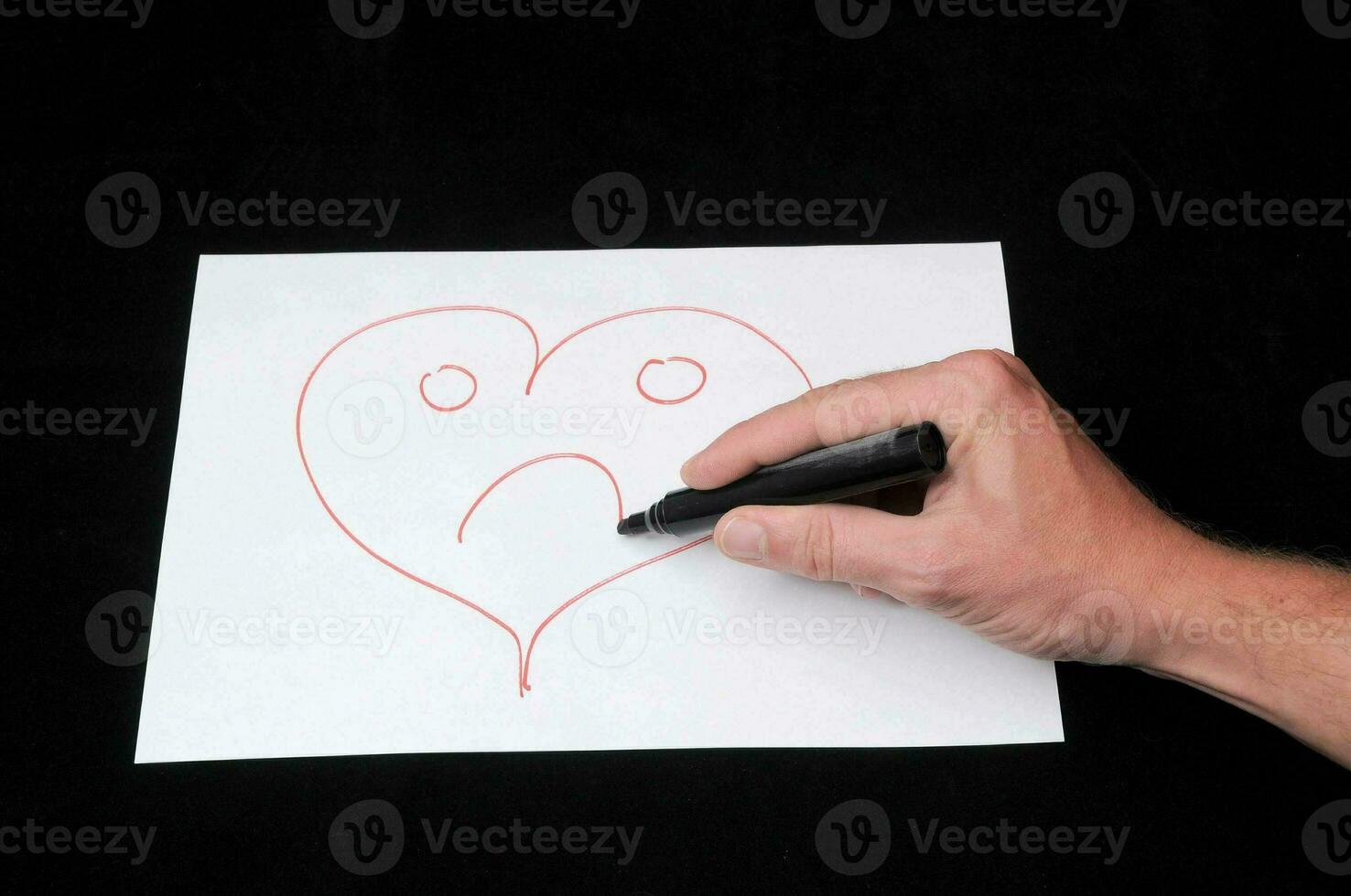 a person drawing a heart with a sad face photo