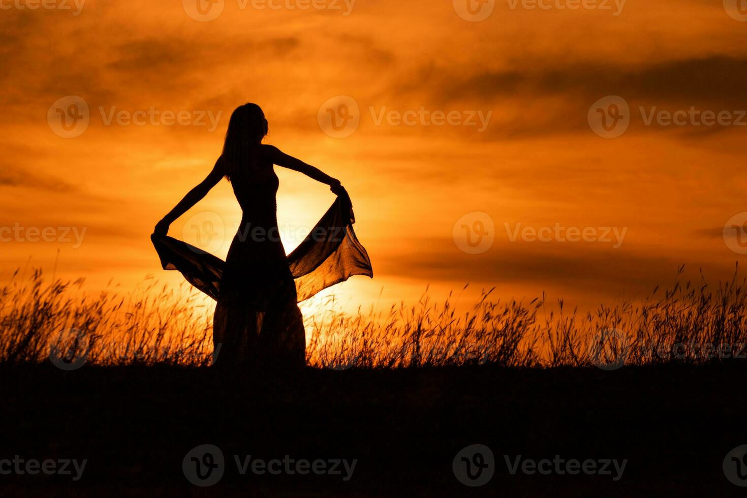 contento mujer bailando y participación bufanda mientras disfruta gasto hora a puesta de sol. foto