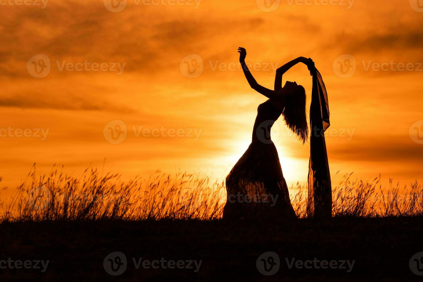 Happy woman dancing and holding scarf while enjoys spending time at sunset. photo