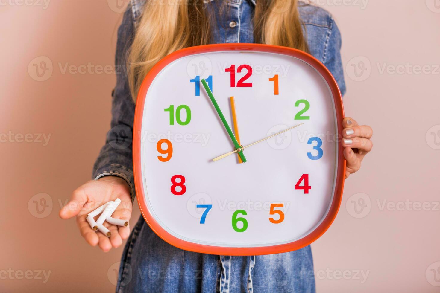 Woman holding broken cigarettes and clock in front of the wall.Quitting smoking concept. photo