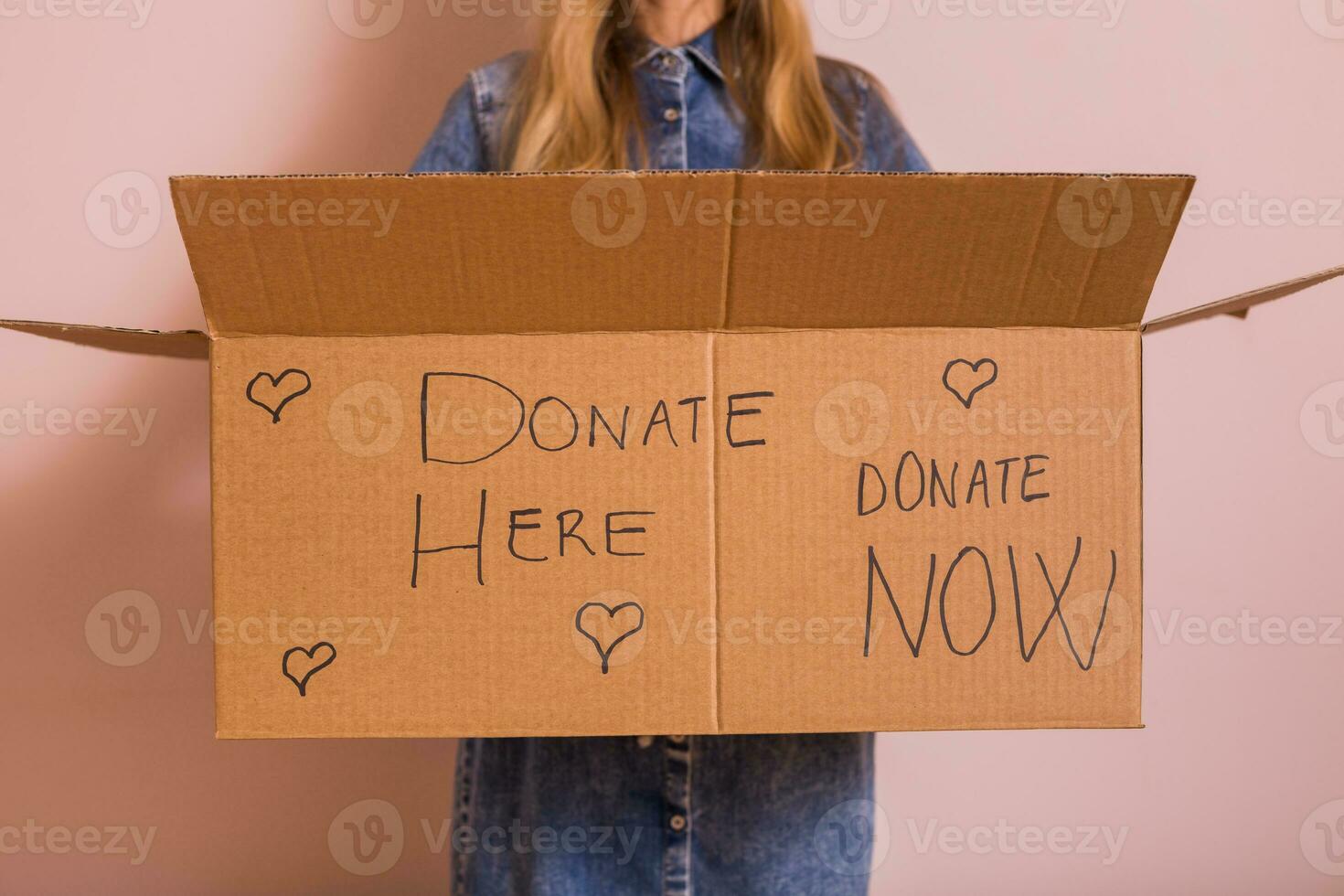 mujer participación donación caja mientras en pie en frente de muro.. foto