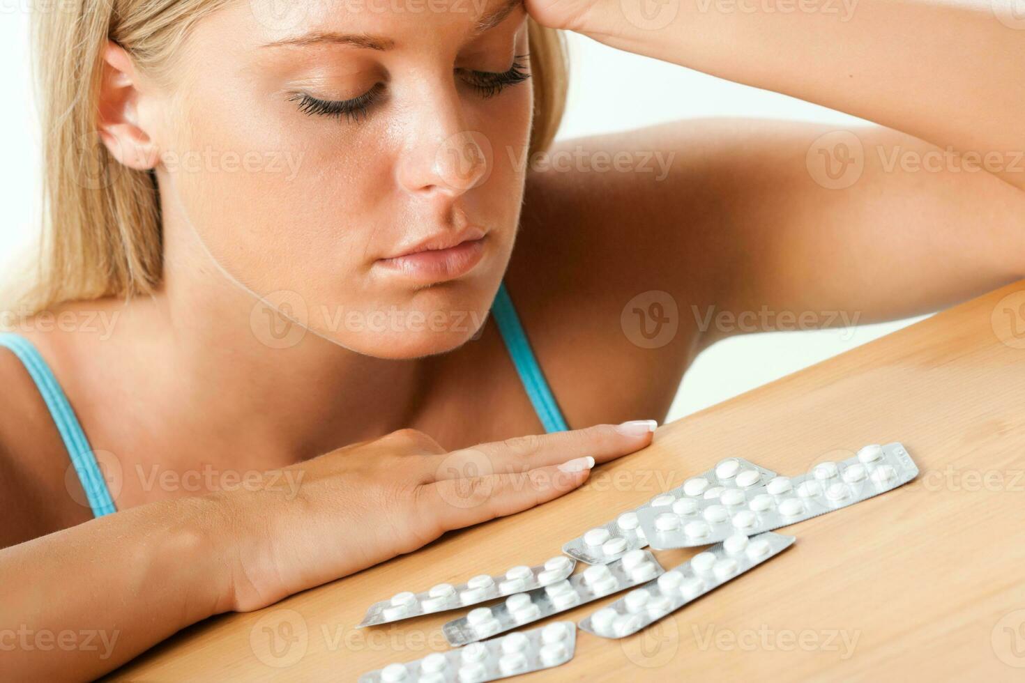 Sad woman looking at pills photo