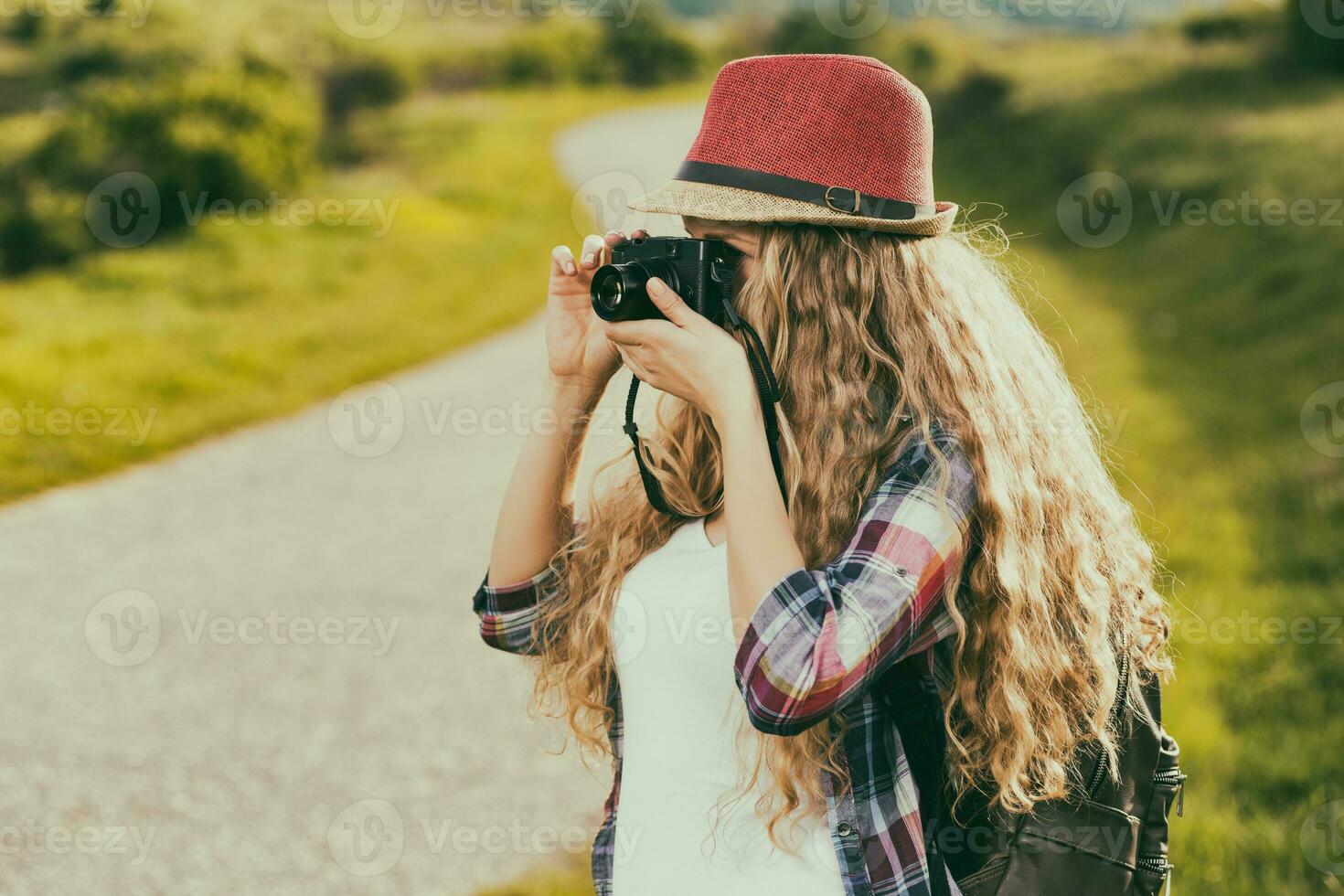 Beautiful young woman at the country road enjoys photographing. photo