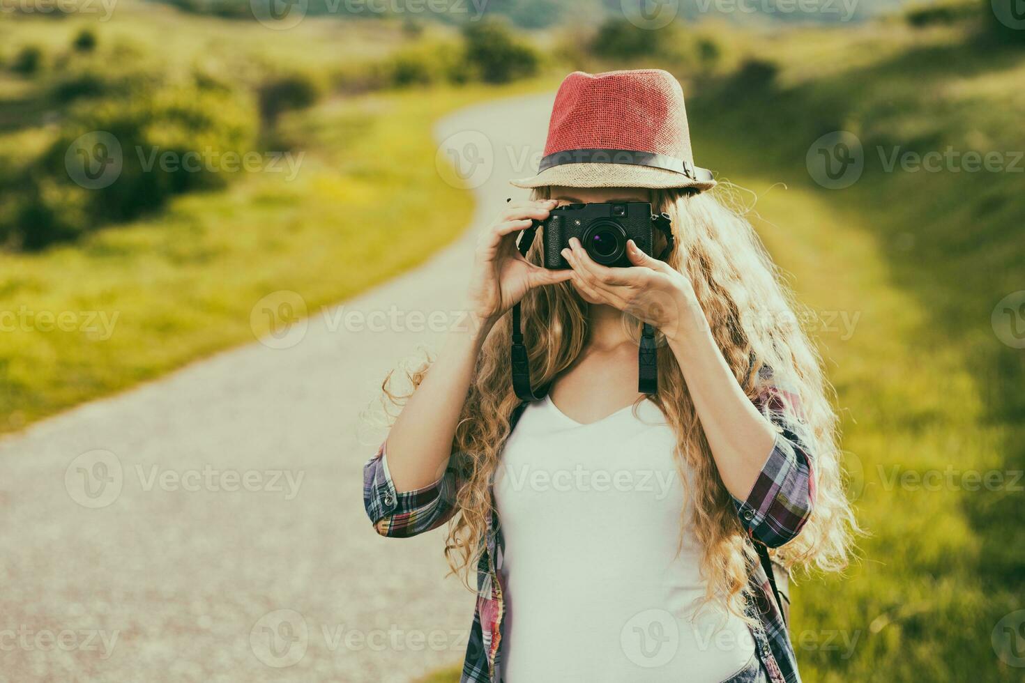 Beautiful young woman at the country road enjoys photographing. photo