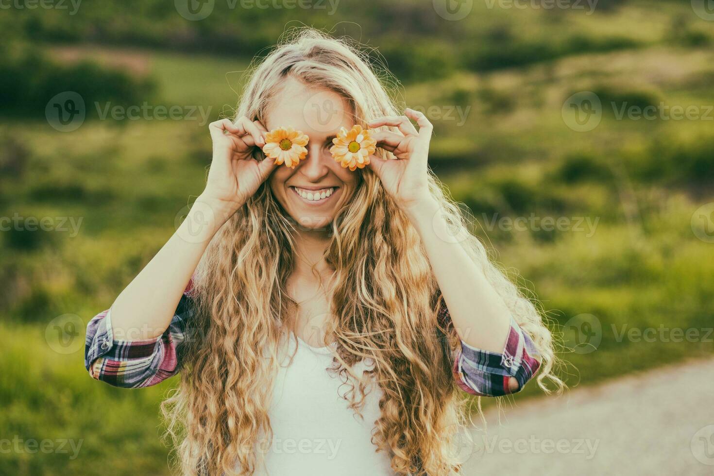 hermosa mujer cubierta ojos con flores a el país carretera.tonificada imagen. foto