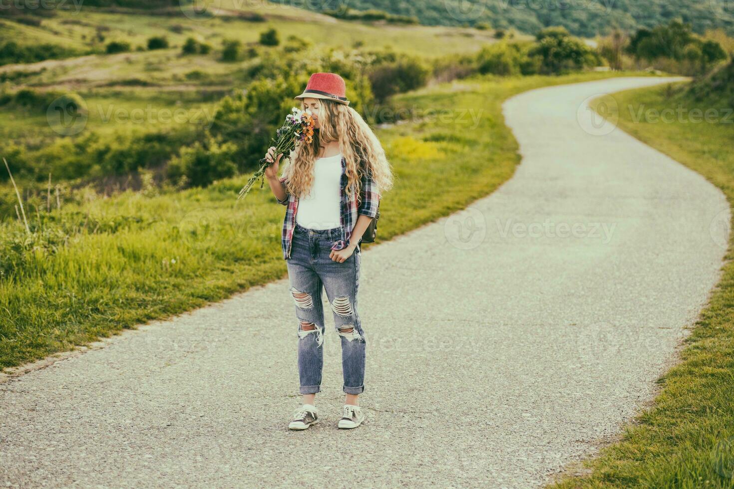 hermosa joven mujer disfruta oliendo ramo de flores de flores a el país carretera.tonificada imagen, foto