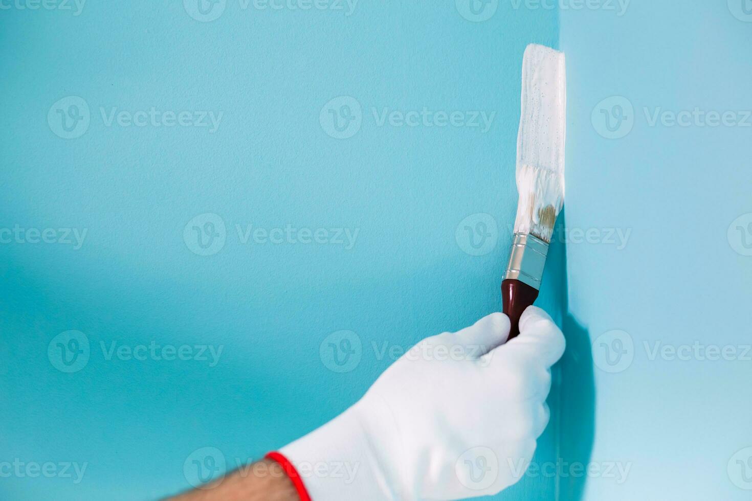 Image of man holding paintbrush and painting blue wall. photo