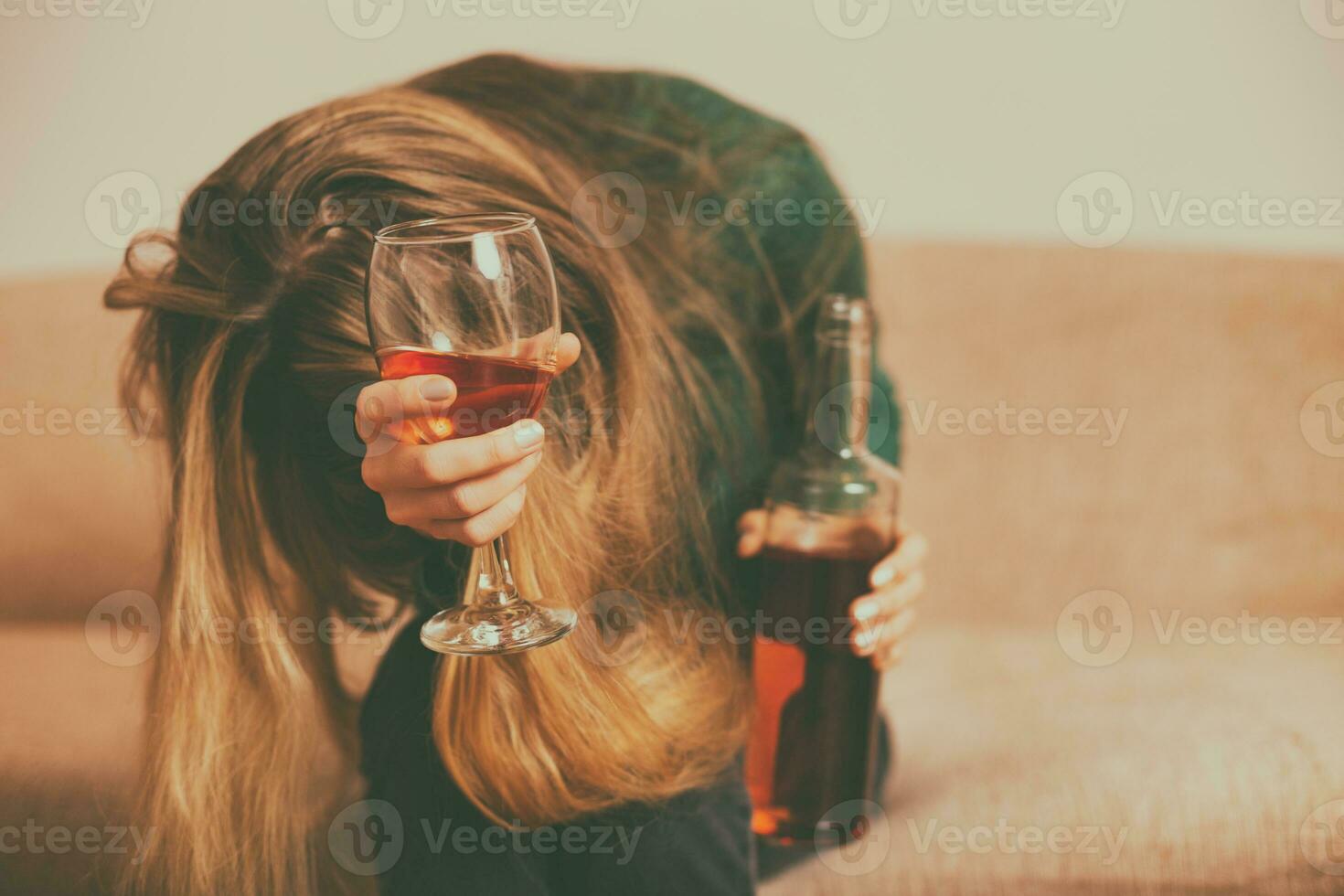 Deprimido mujer Bebiendo alcohol mientras sentado solo a sofá.tonificado imagen. foto