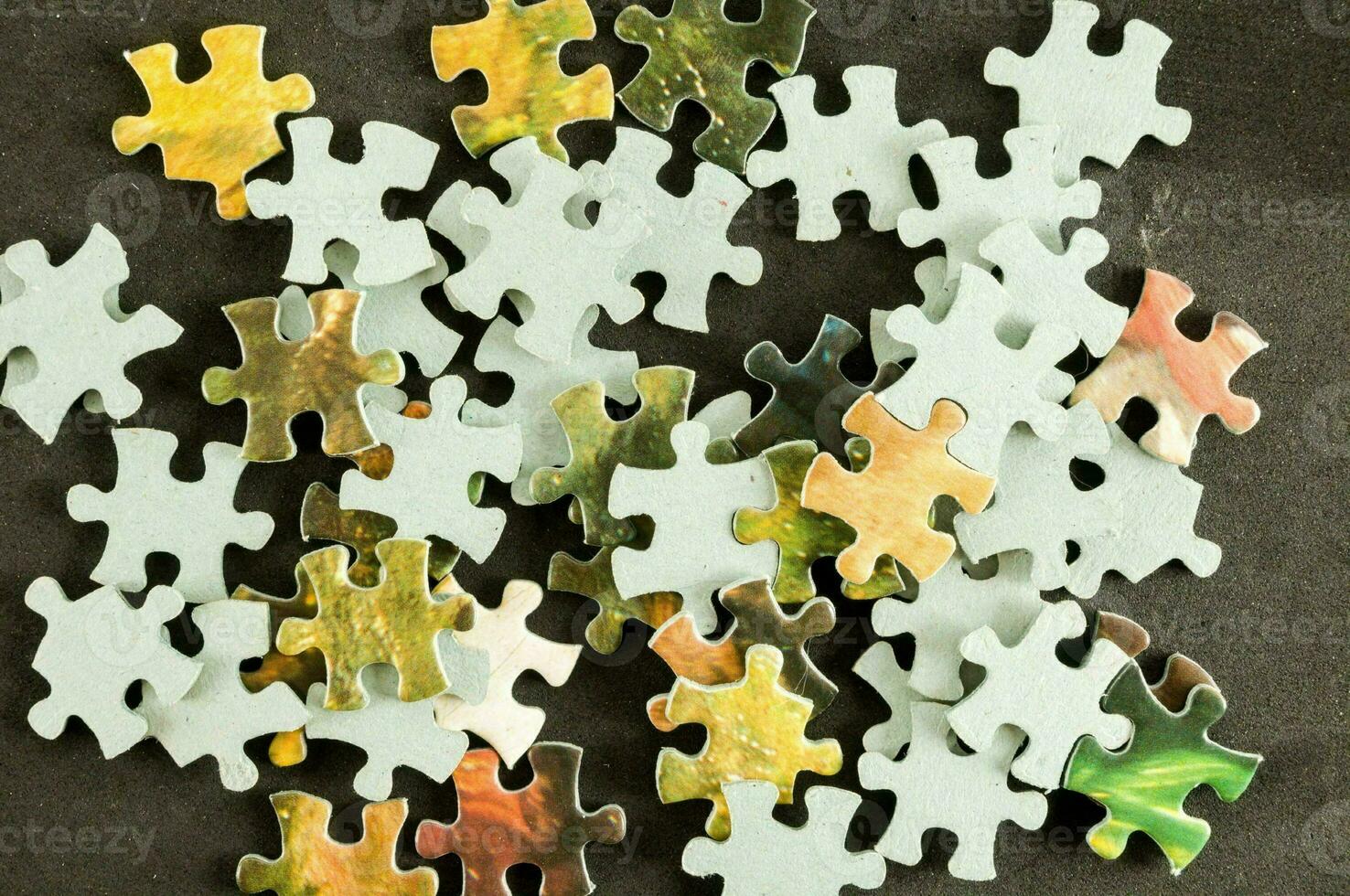 a pile of puzzle pieces on a black surface photo