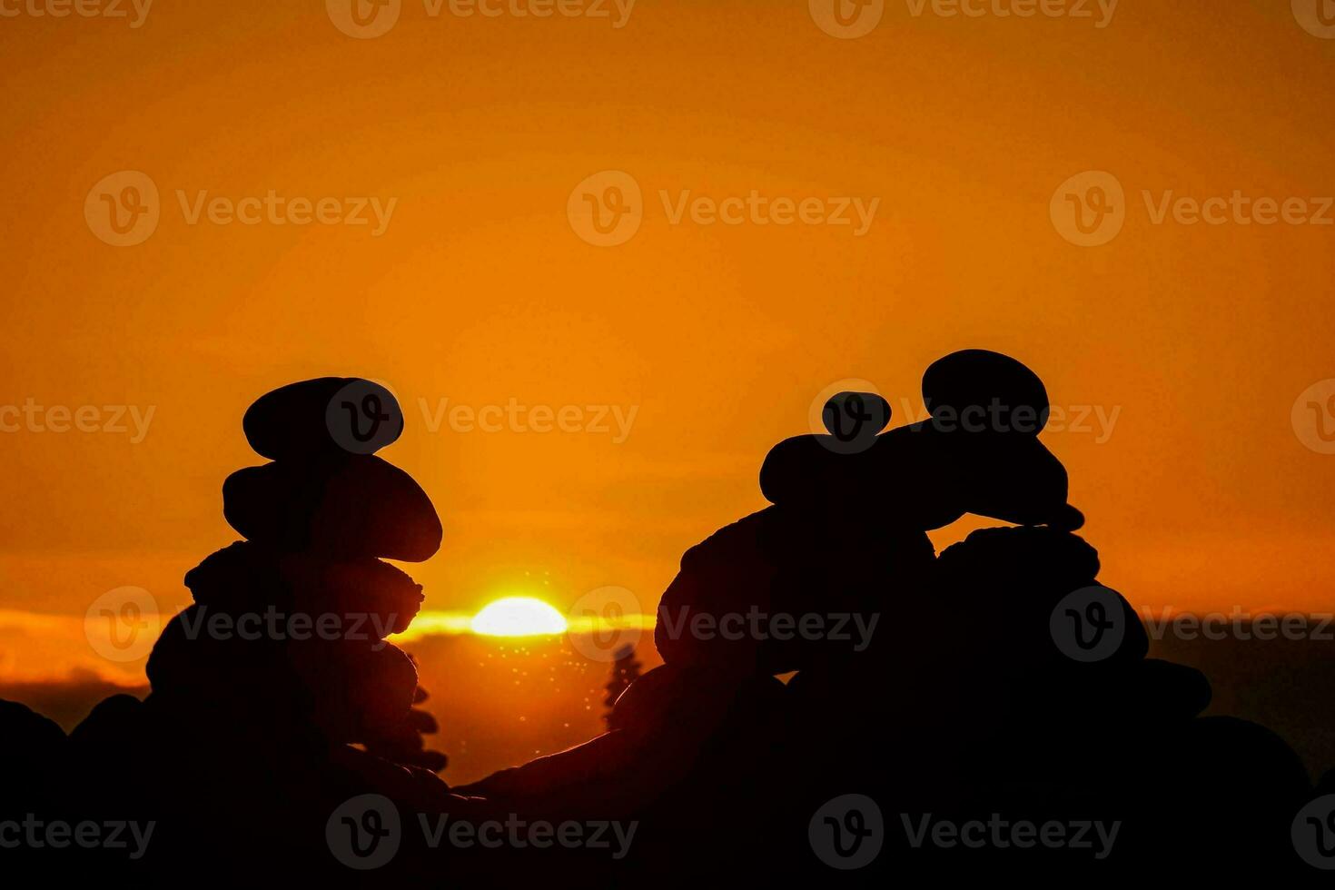 the sun setting over a pile of rocks photo