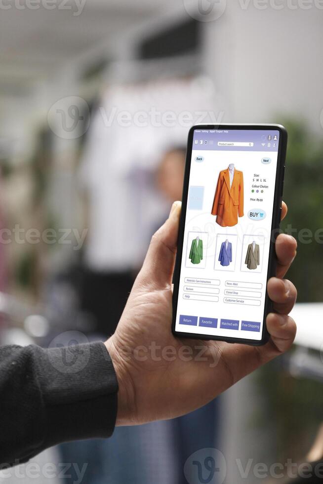 Male individual blogging or creating content specifically focused on digital devices, with an emphasis on cellphones. Closeup on caucasian man holding smartphone showing promotional clothing content. photo