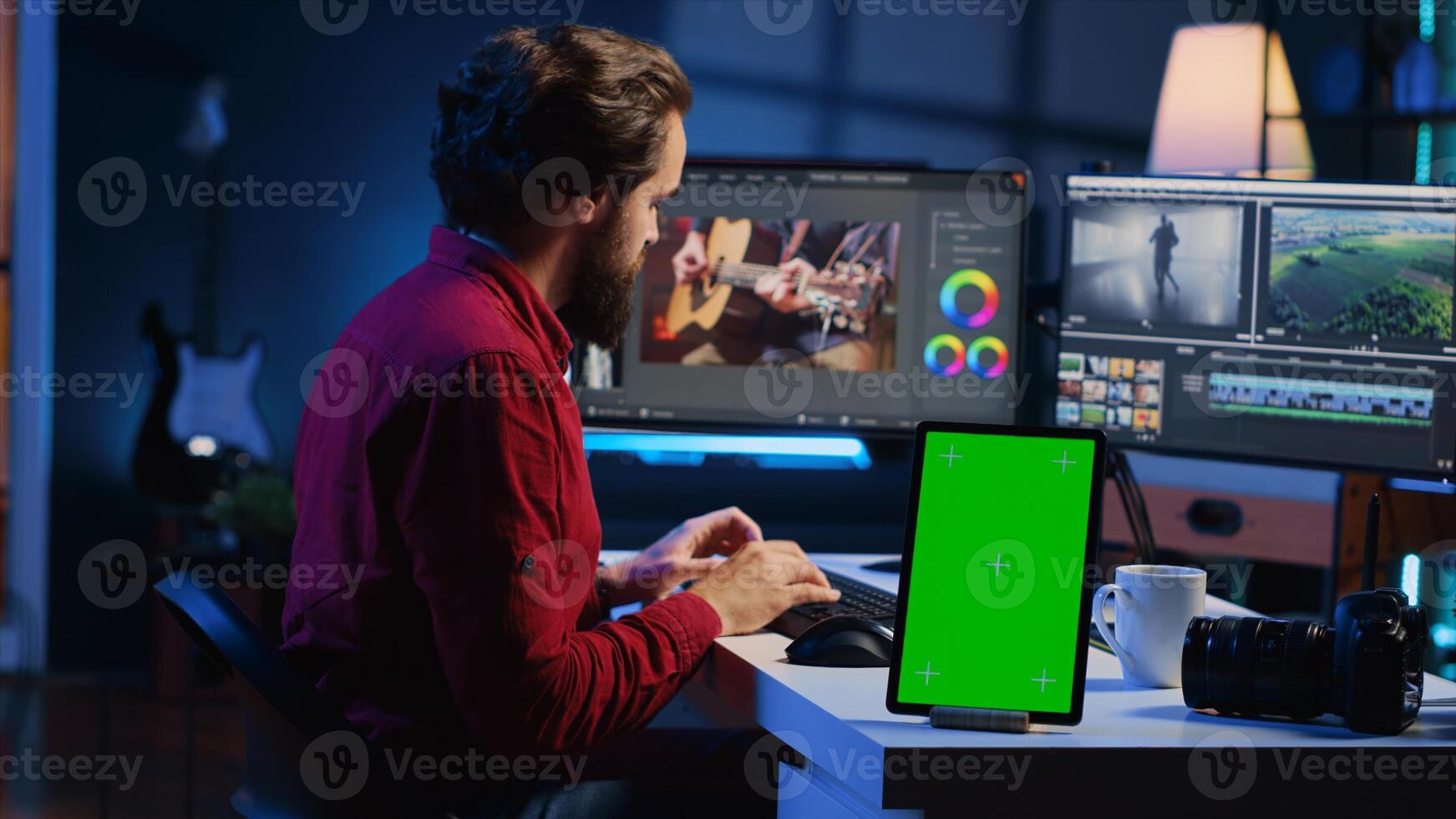 Video editor adds sound effects to filmed footage, working in post production studio with green screen tablet. Videographer using headphones to test and improve audio quality next to mockup device photo