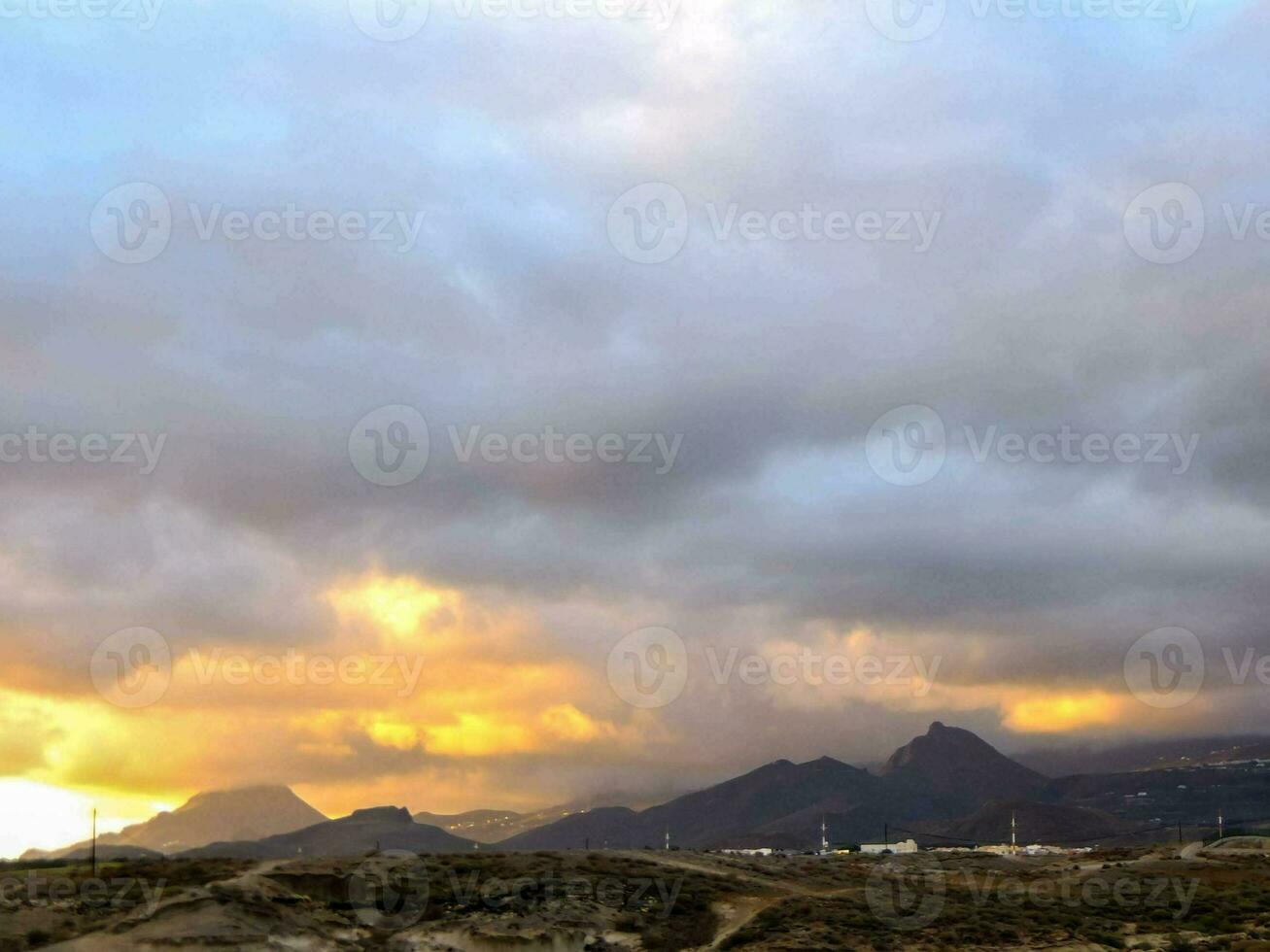 a sunset over the mountains with clouds photo