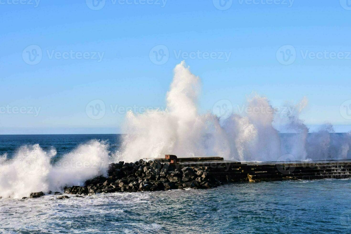 un grande ola estrellarse dentro el rocas a el Oceano foto
