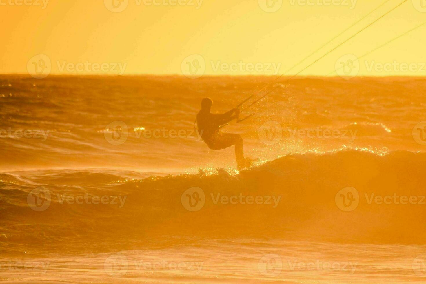 a man kite boarding in the ocean at sunset photo