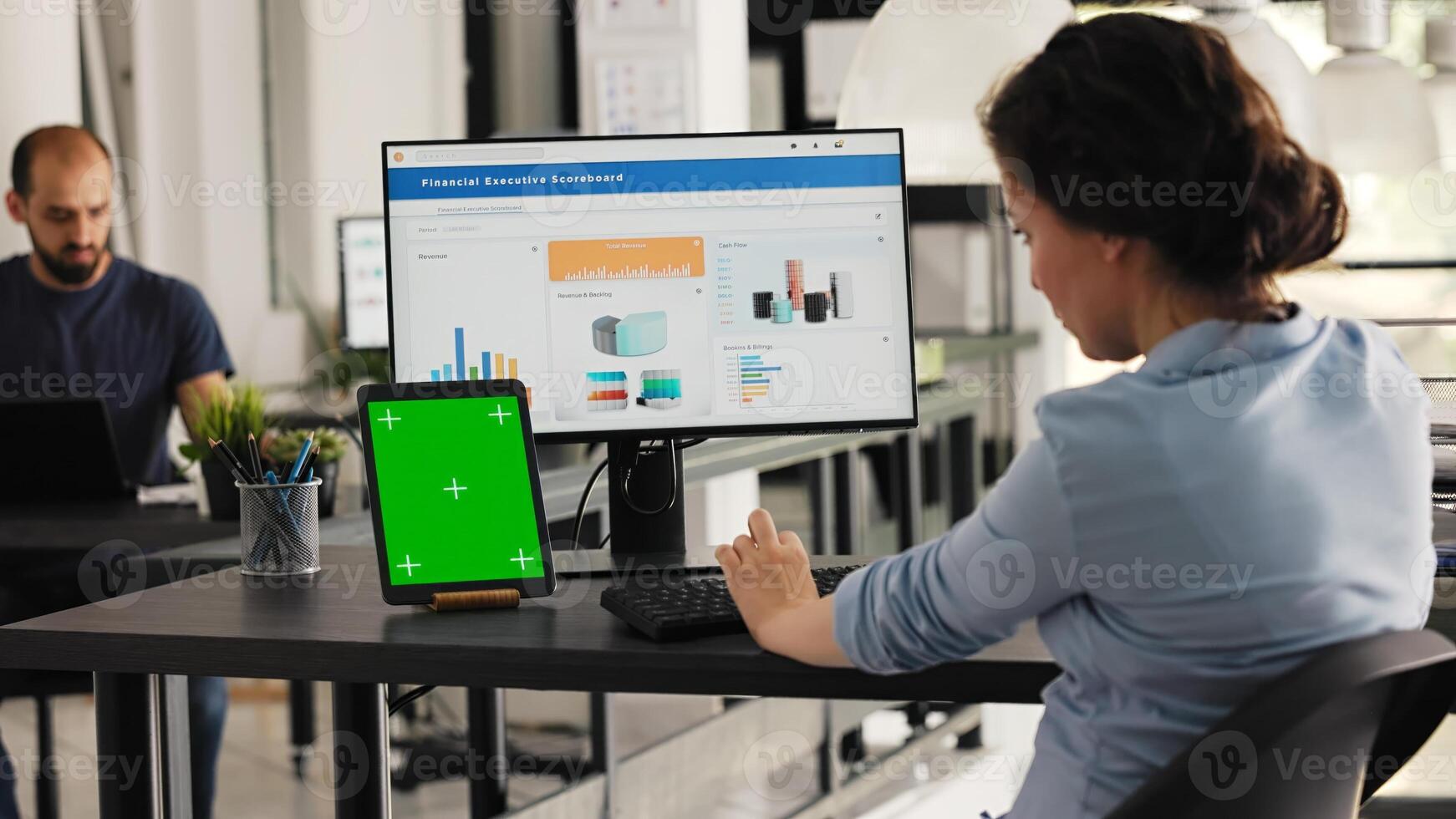 Manager uses greenscreen on tablet in coworking space office, presenting isolated copyspace layout on modern gadget. Businesswoman using pc desktop and chromakey screen at desk. Handheld shot. photo