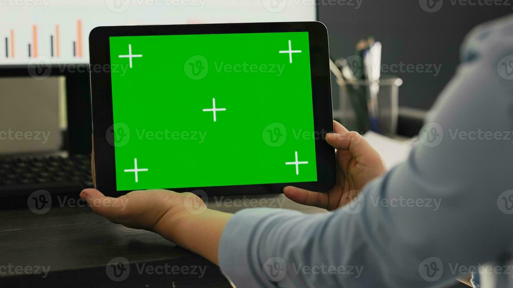POV of manager holds smartphone with isolated greenscreen layout, working with blank mockup chromakey template at office desk. Young man looking at mobile device display with copyspace. photo