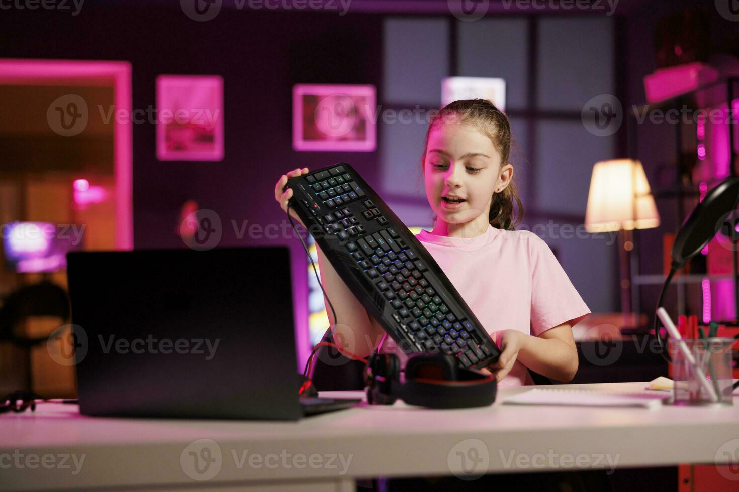 Happy child reviewing mechanical keyboard received from sponsoring brand to promote it. Young media star advertising wireless Bluetooth computer peripheral from partnering company photo