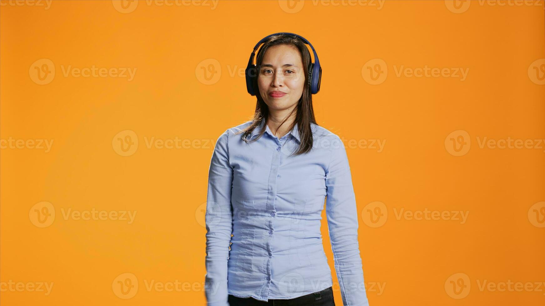 Funky woman listening to songs on headset gadget and dancing in studio, having fun with radio music on audio headphones. Cheerful girl presenting groovy dance moves and enjoying rhythm. photo