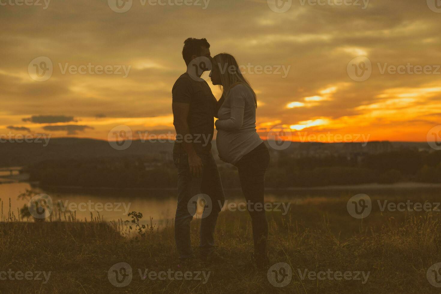 Husband kissing his pregnant wife while they enjoy spending time together outdoor.Toned image. photo