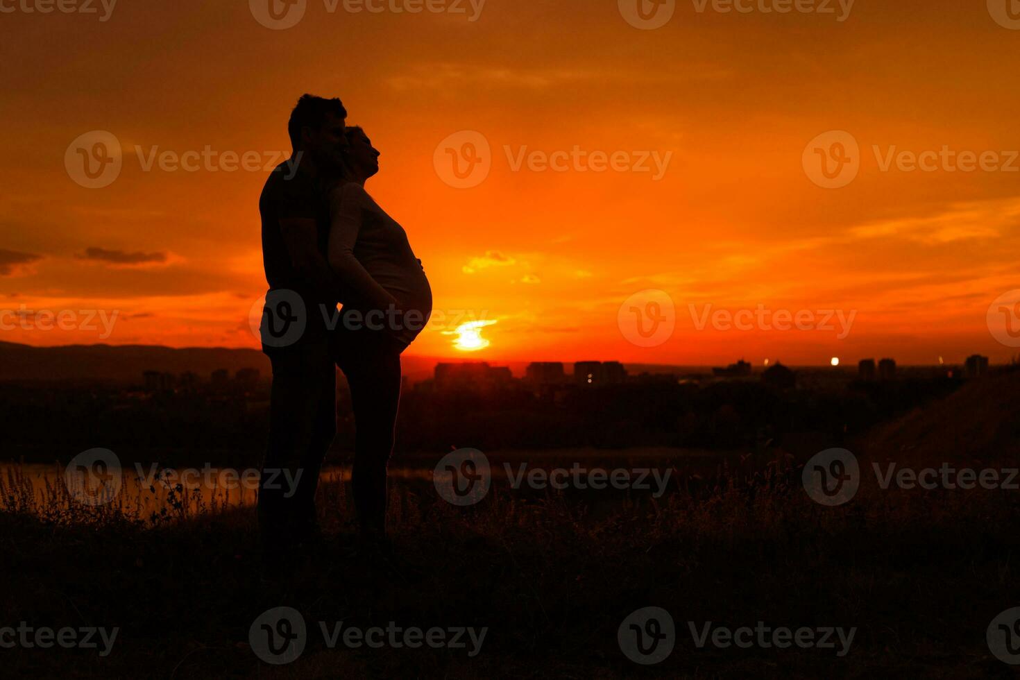 Silhouettes of husband and pregnant wife enjoy spending time together outdoor.Toned image. photo