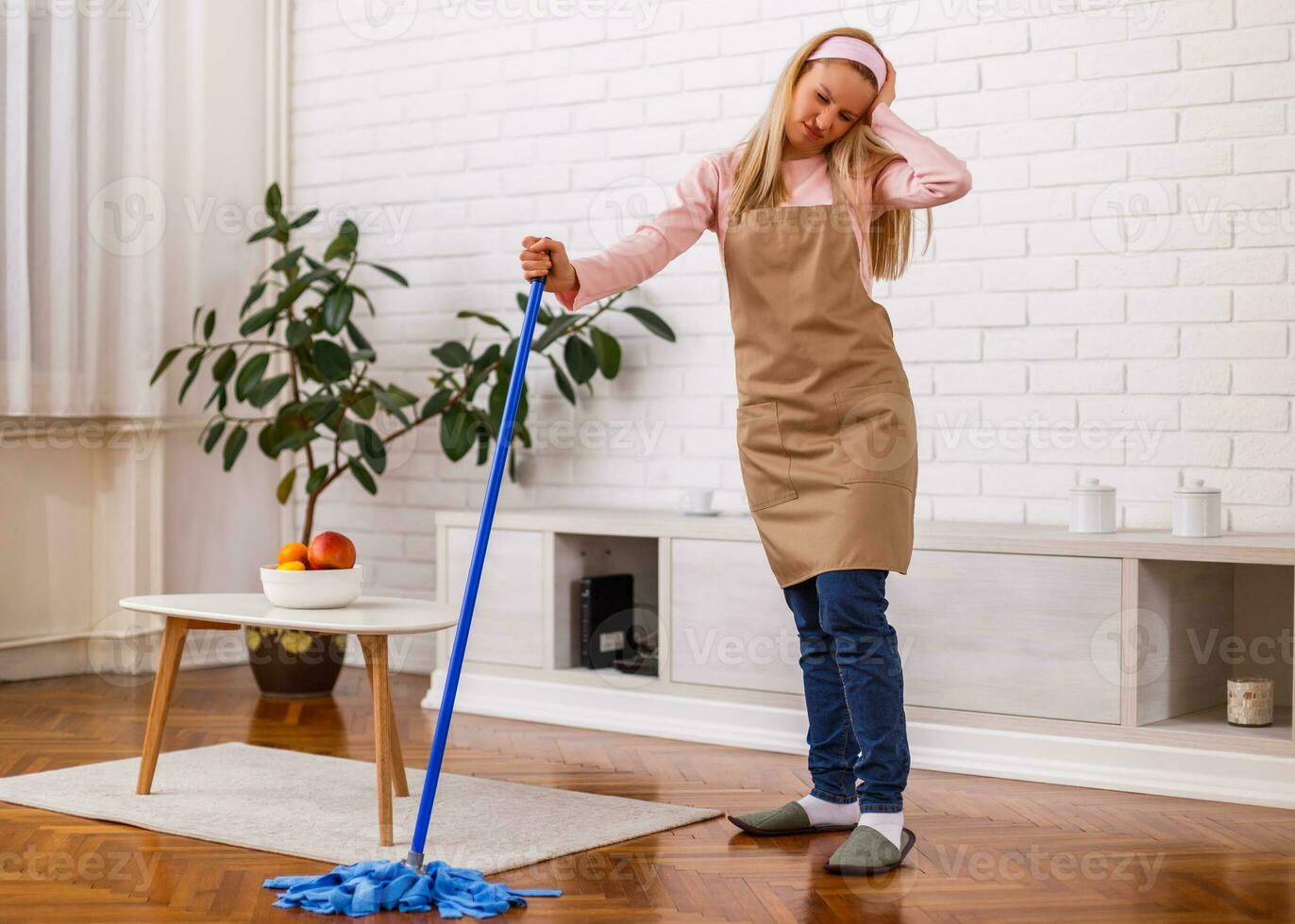 Tired housewife cleaning living room with a mop. photo