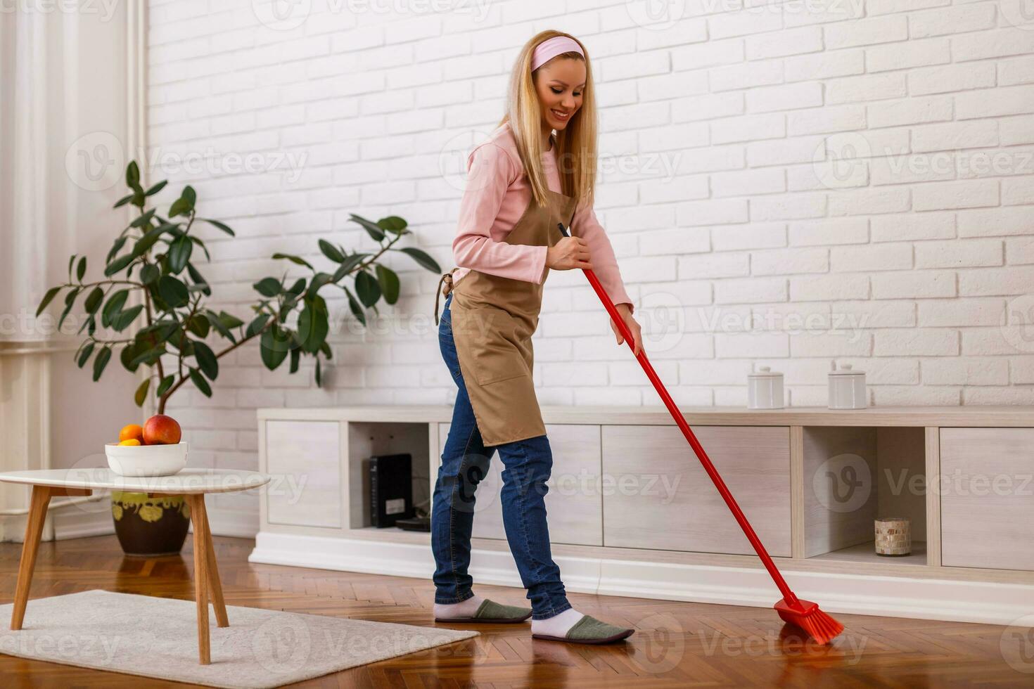 Beautiful housewife cleaning with broom her home. photo