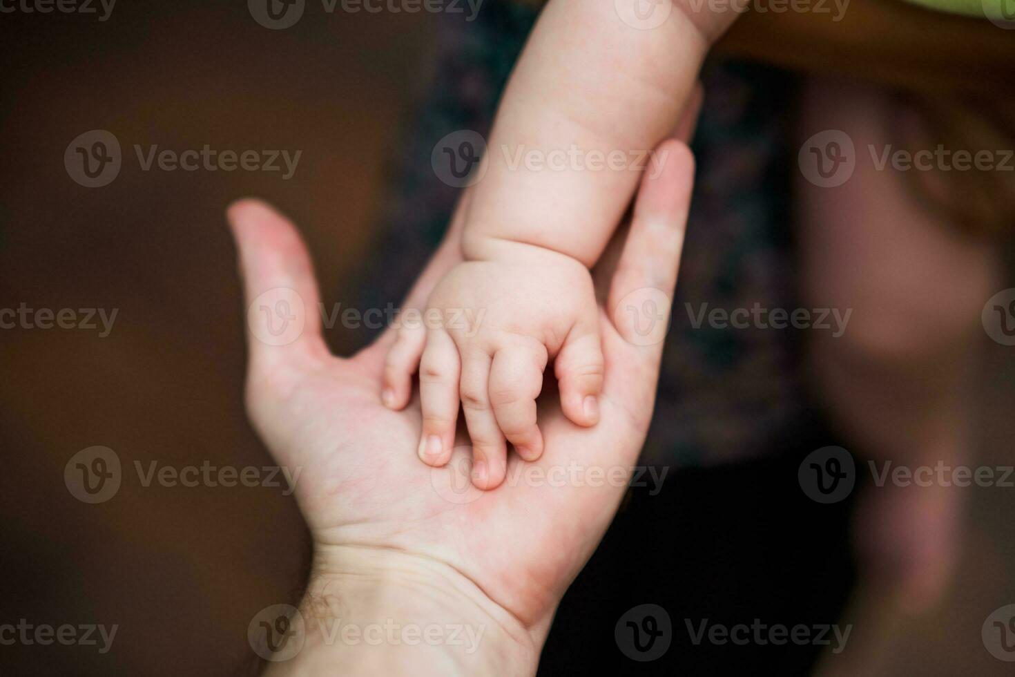 Close up image of  father's   and his baby boy son hands holding each other. Focus on fingers. photo