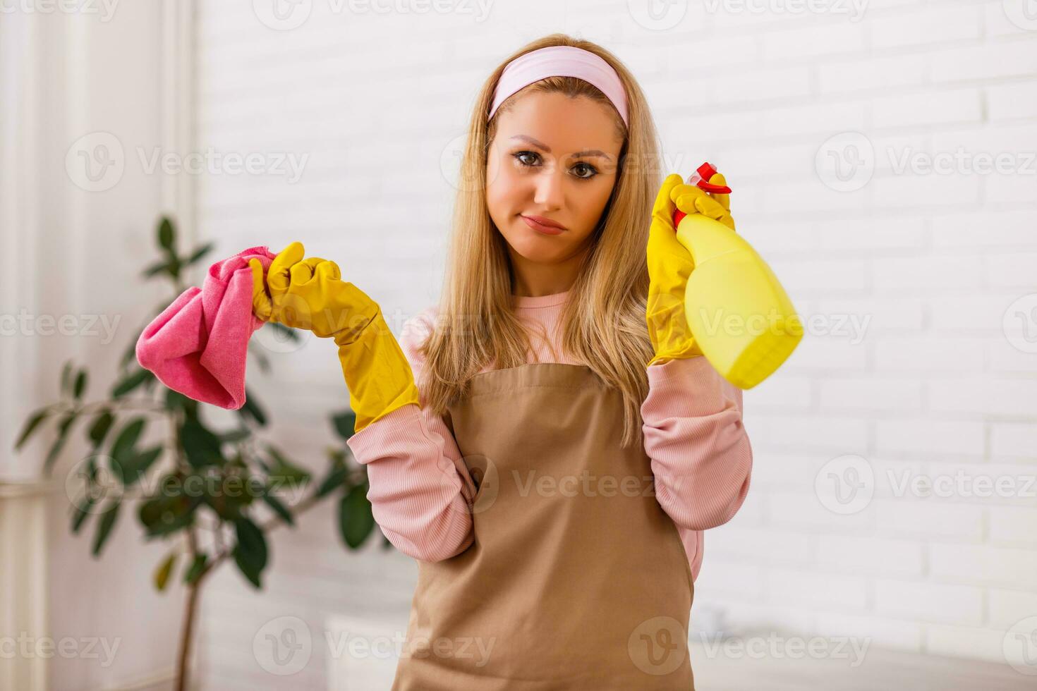 Tired housewife with cleaning equipment standing in the living room. photo