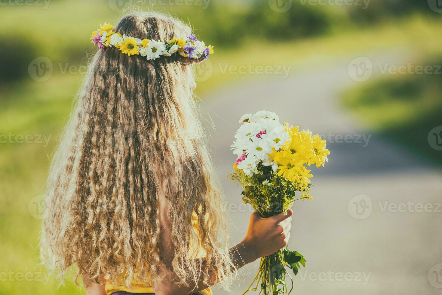 Beautiful blonde woman with long hair and  wreath holding flowers in nature. photo