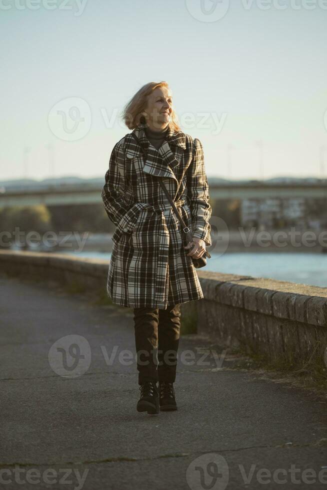 Senior woman enjoys walking by the river.Toned image. photo