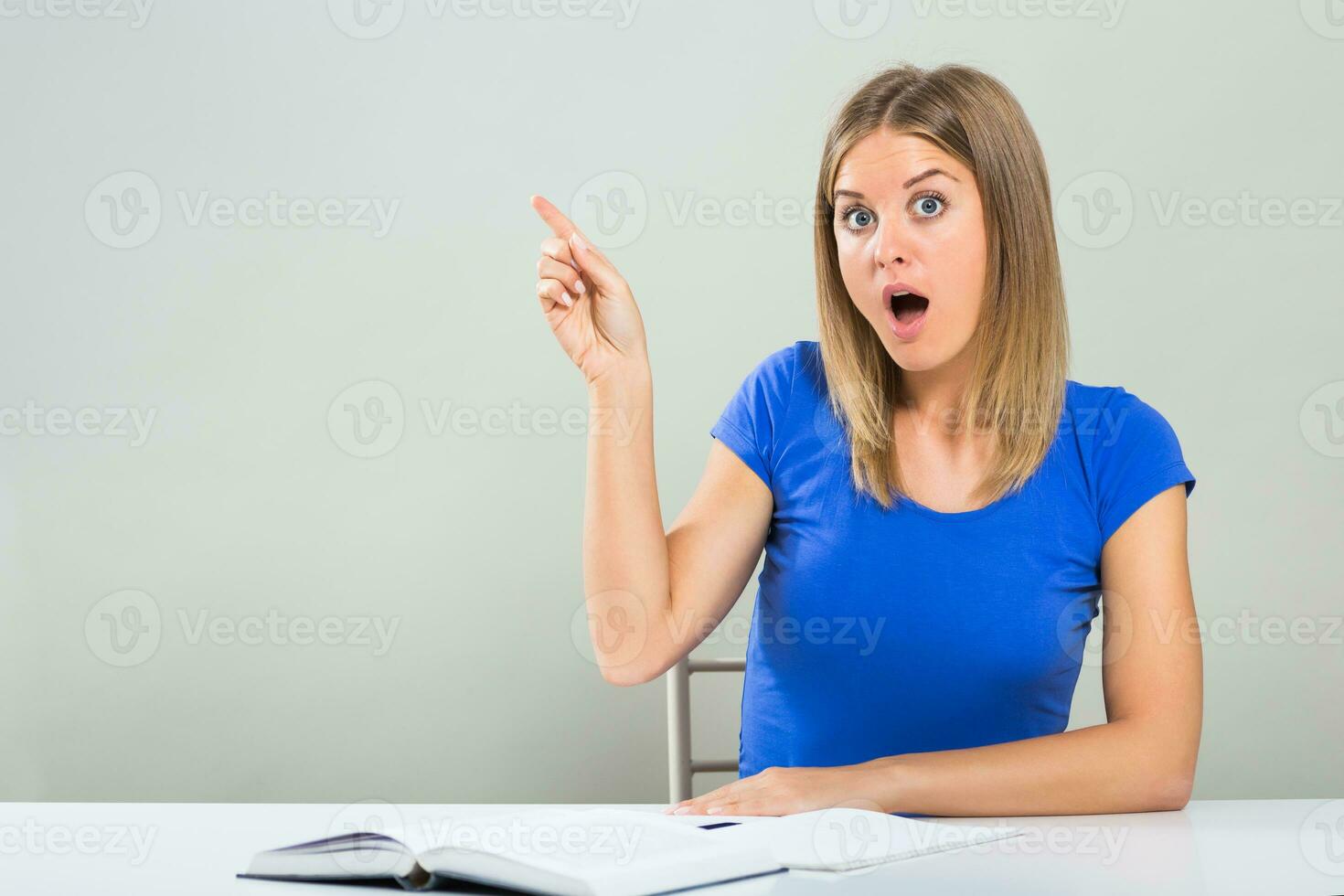 Excited female student sitting at the table and pointing. photo