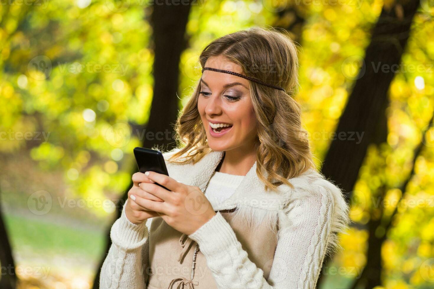 Beautiful boho girl texting message in the park. photo