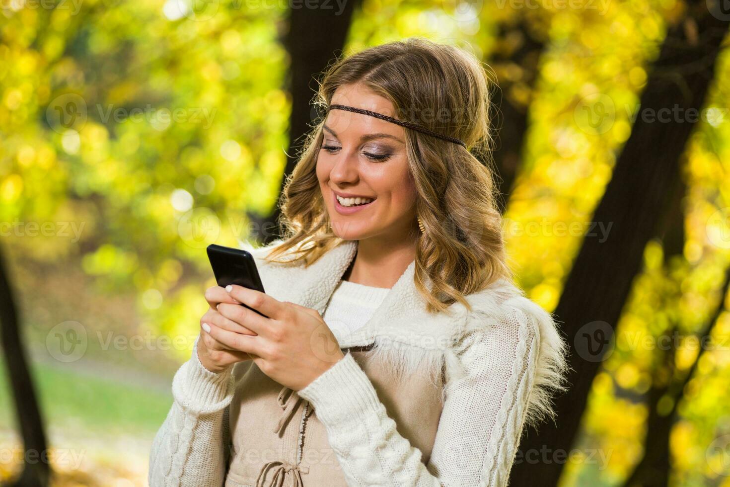 Beautiful boho girl texting message in the park. photo