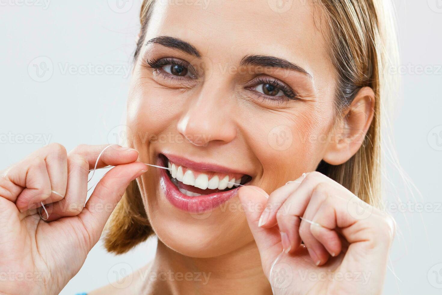 Woman cleaning teeth with dental floss photo