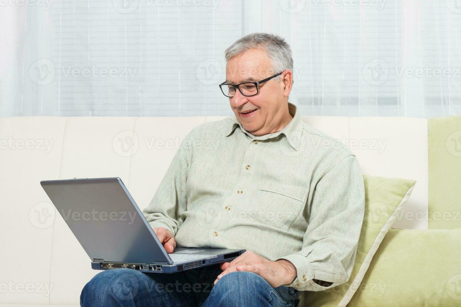 Senior man showing thumb up while using laptop. photo