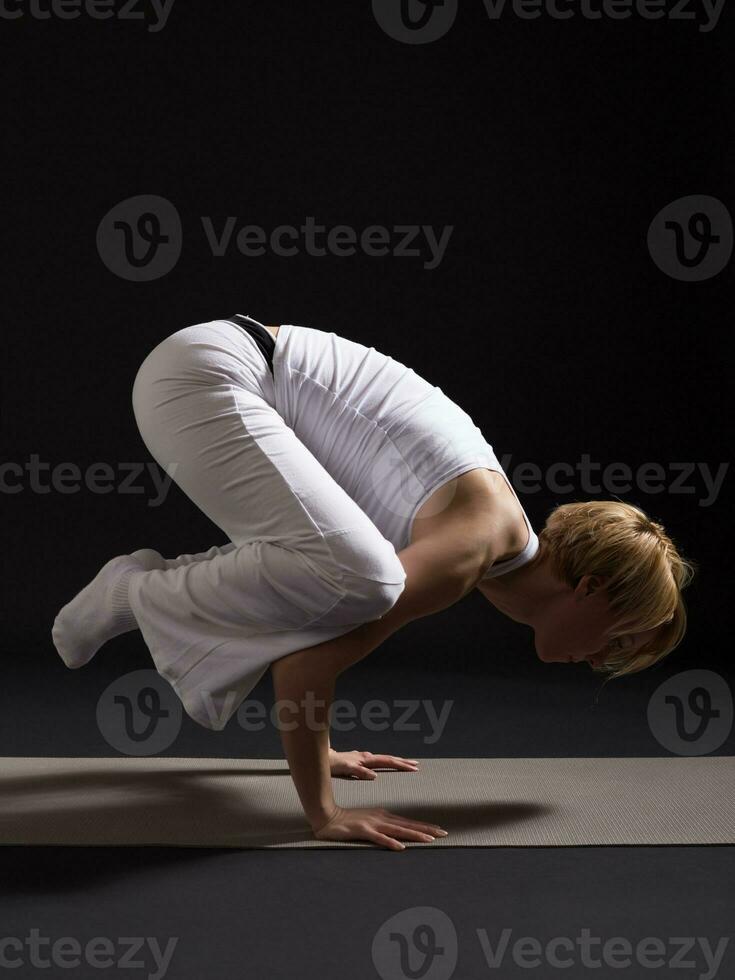 Woman exercising yoga indoor on black background, photo