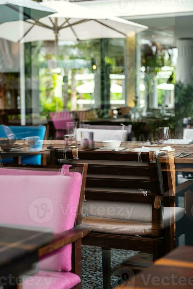 Hotel restaurant space with tables set for dinner at luxury resort, view through by window. photo