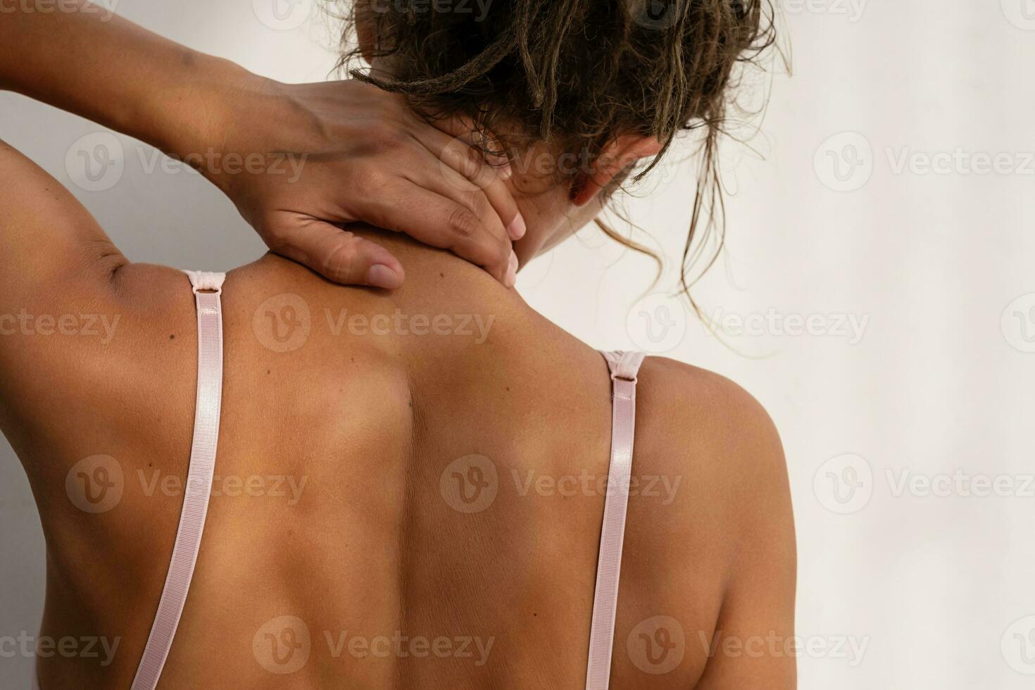 Woman touching her neck rear view, copy space. photo