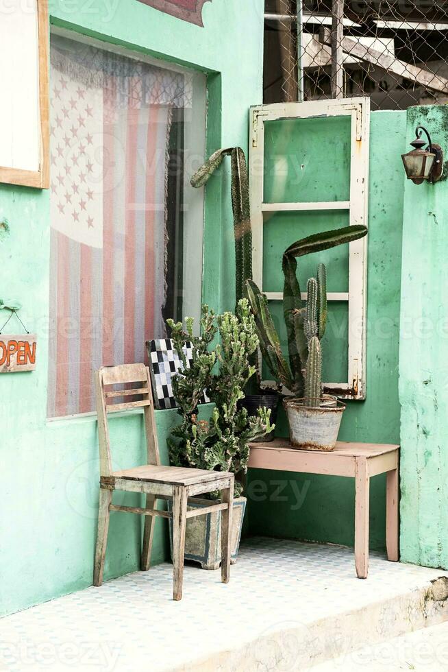 antiguo silla y cactus cerca frente puerta de pequeño Clásico país almacenar. foto