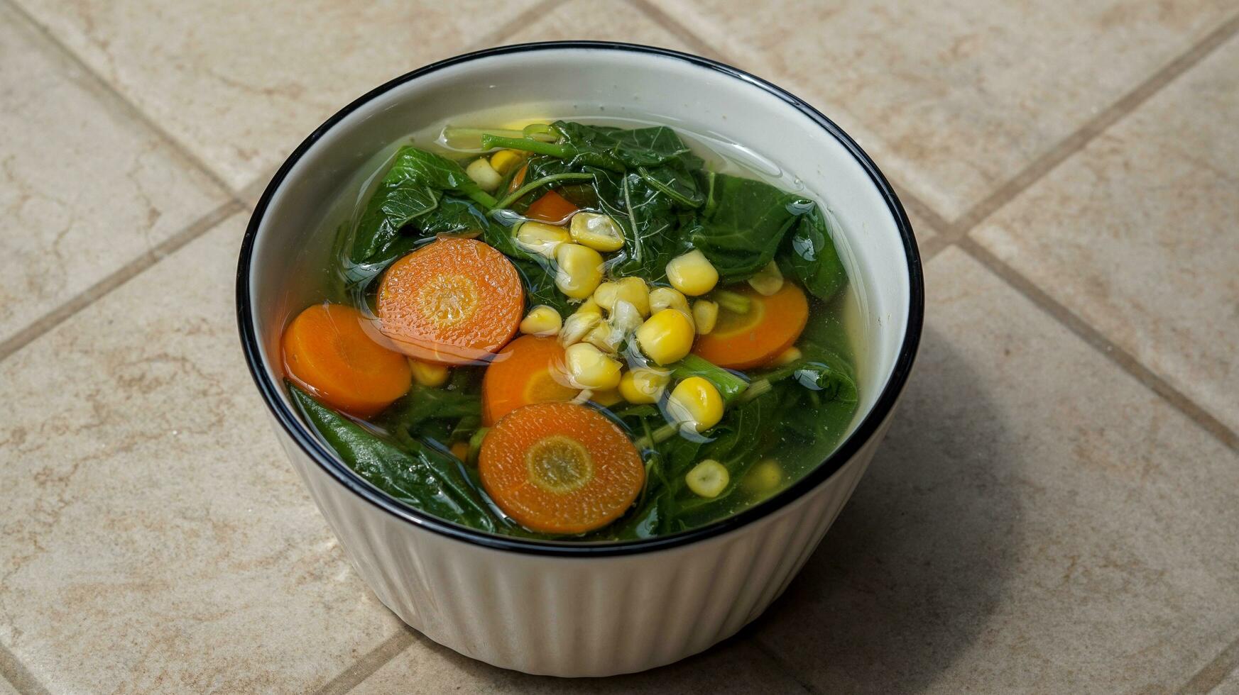 vegetable soup filled with spinach, corn and carrots photo