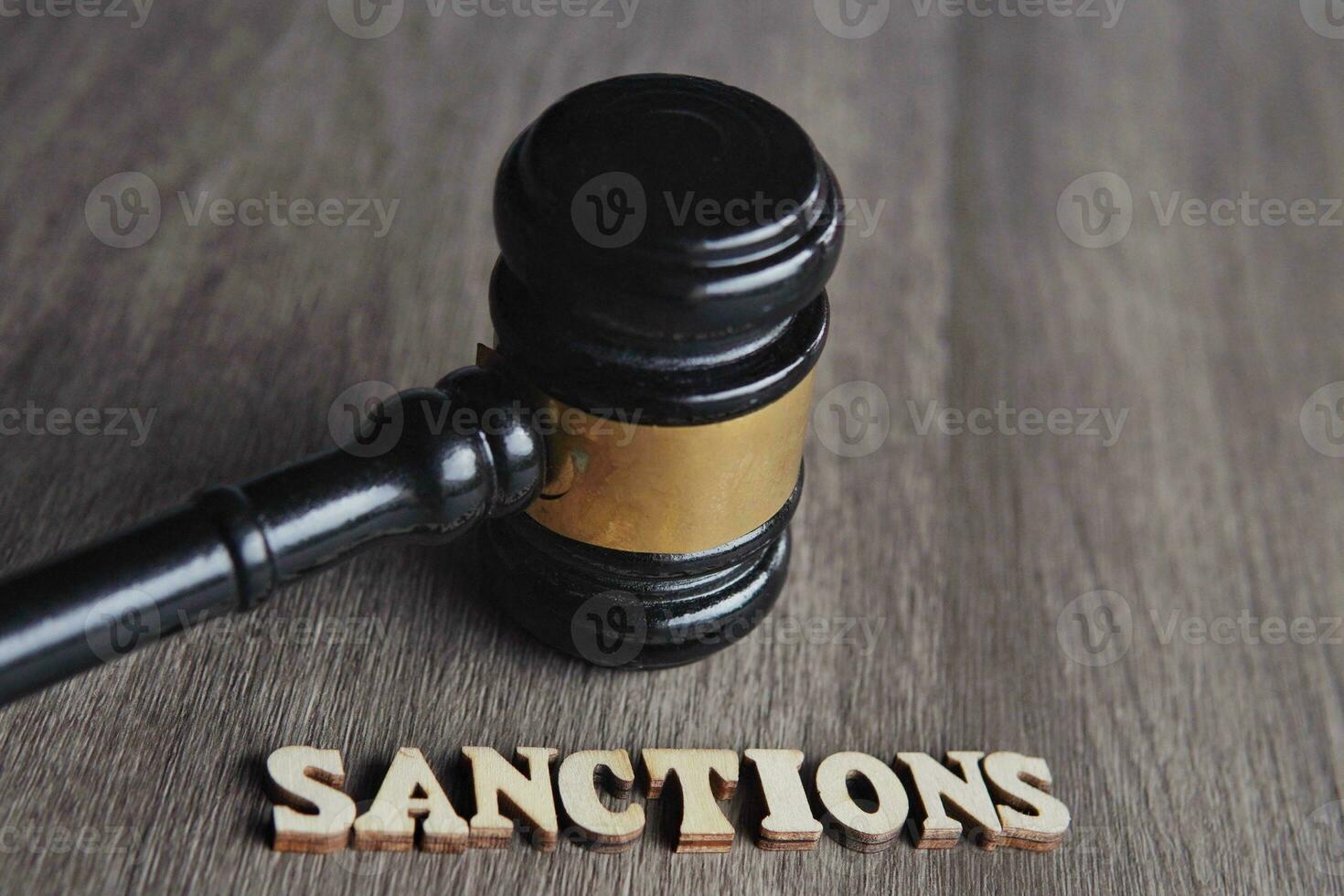 Close up image of judge gavel and text SANCTIONS on wooden table. photo
