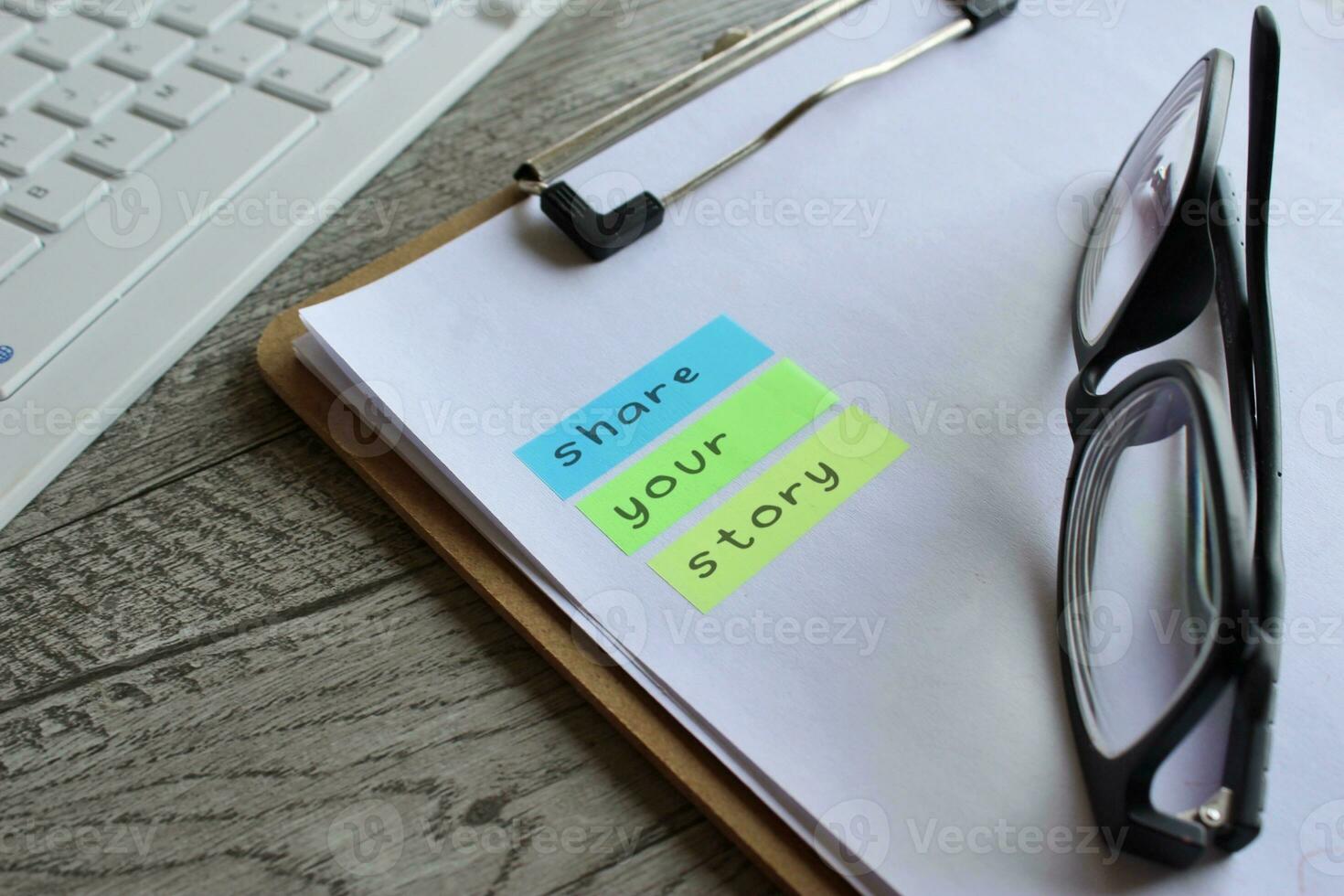 Closeup image of paper clipboard with text SHARE YOUR STORY. photo