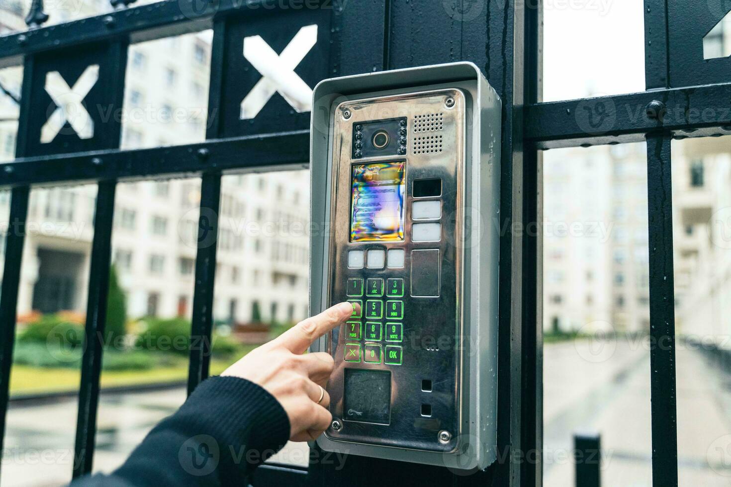 Female Hand Operating Video Intercom System, Dialing Apartment Number in Urban Residential Complex photo