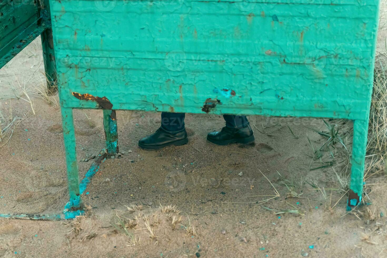 Woman's Feet in Autumn Boots and Jeans Next to Old Changing Cabin on Autumn Beach photo